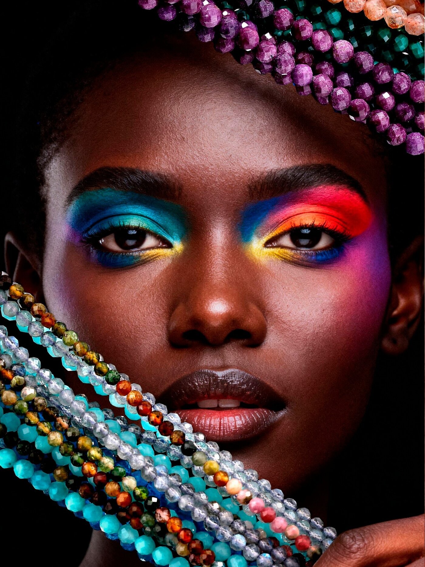 Editorial portrait holding multicolor faceted gemstone strands